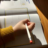 Hand mit Bleistift schreibt auf Buchseite